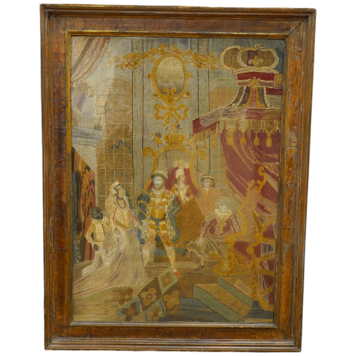 A large unusual Regency framed silk worked embroidery depicting Henry VIII in court with three courtiers and a blackamoor servant holding the dress of a young female courtier as she enters, worked mainly in long stem sti